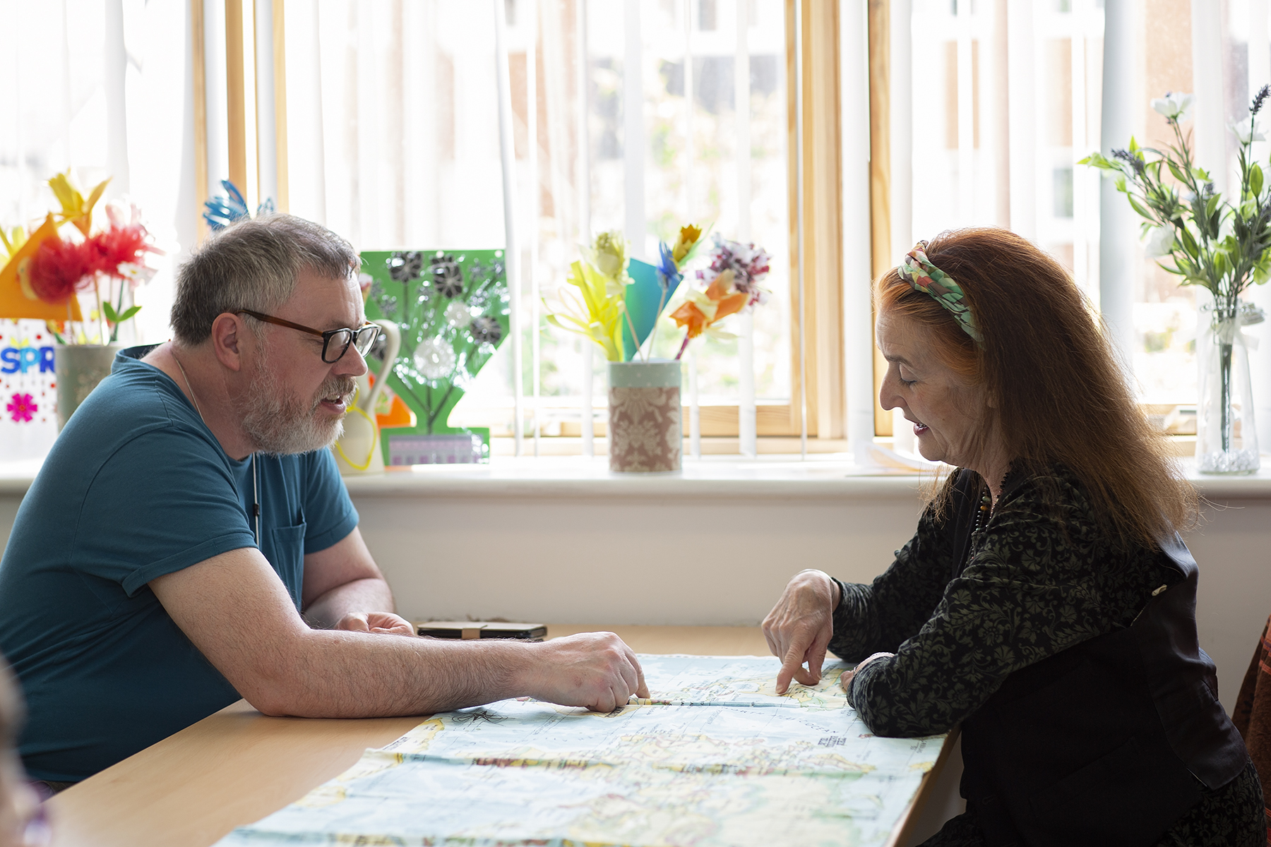 Two people chatting and sitting at a table at Golau Caredig