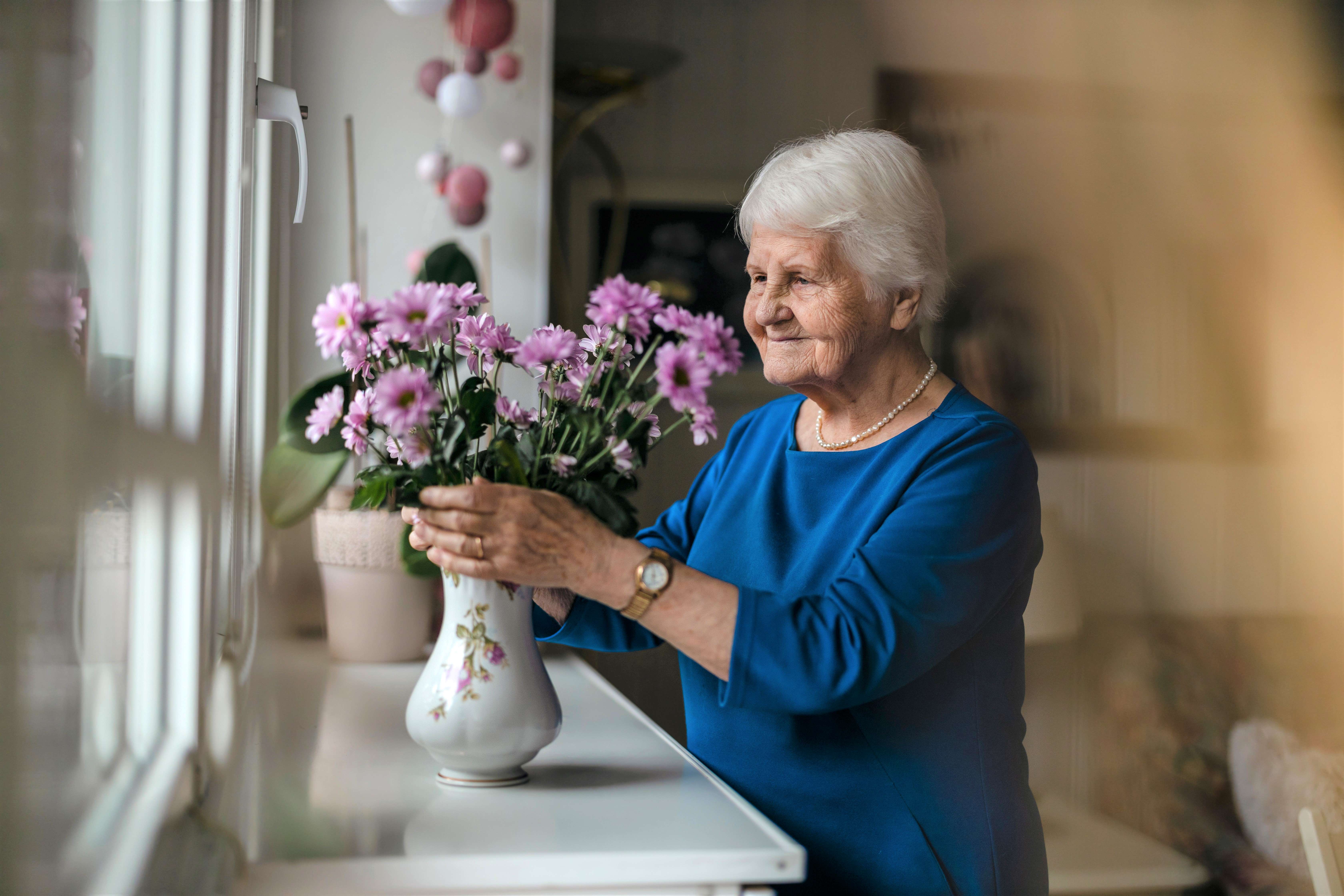 Lady adjusting flowers in a vase on the windowsill