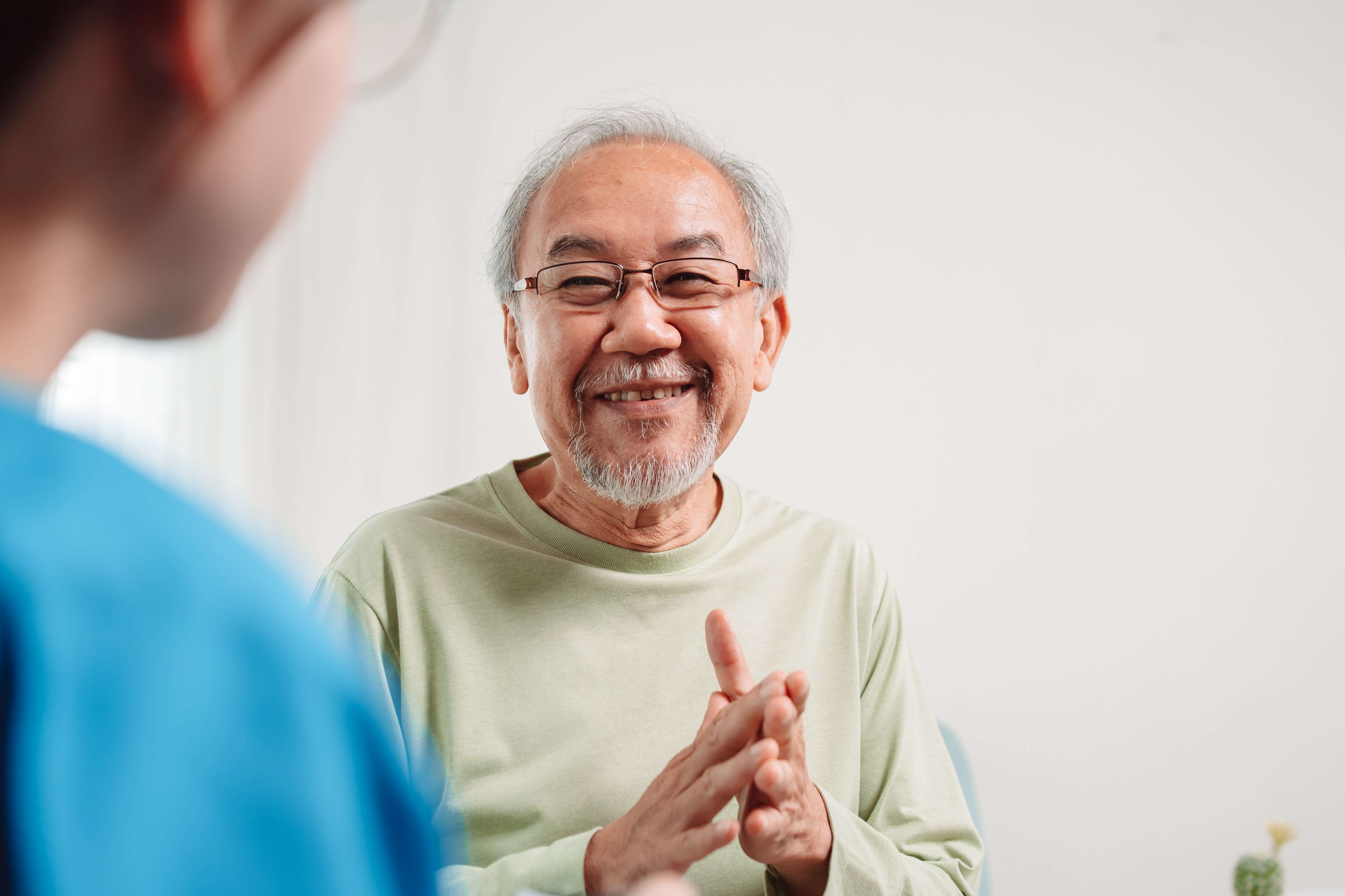 An older man smiling and chatting with his carer