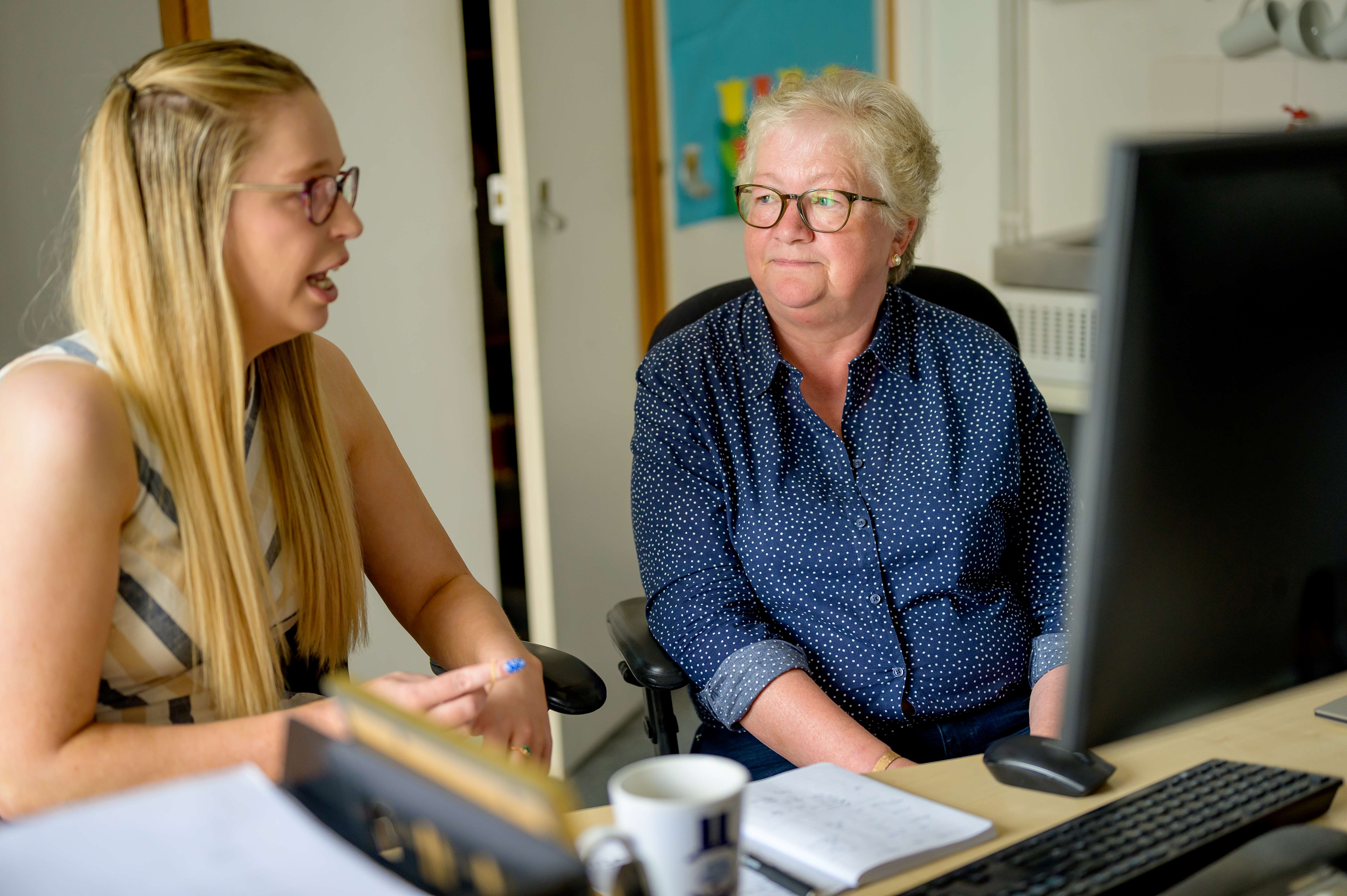 Two ladies sat at a computer chatting